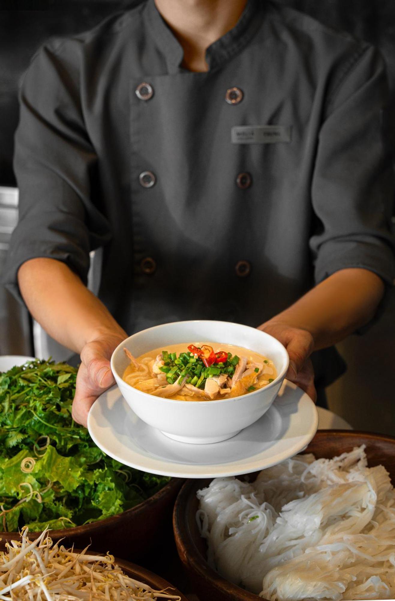 Melia Vinpearl Hue Hotel Bagian luar foto A chef holding a bowl of Tom Kha soup